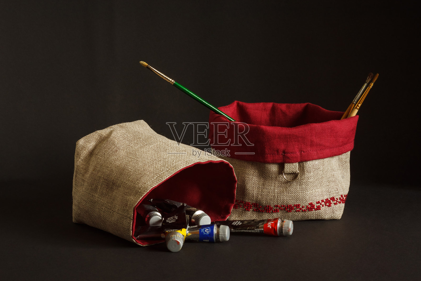 带有红色刺绣装饰的物品袋。由亚麻布制成。画笔放在袋子里。黑色背景。照片摄影图片