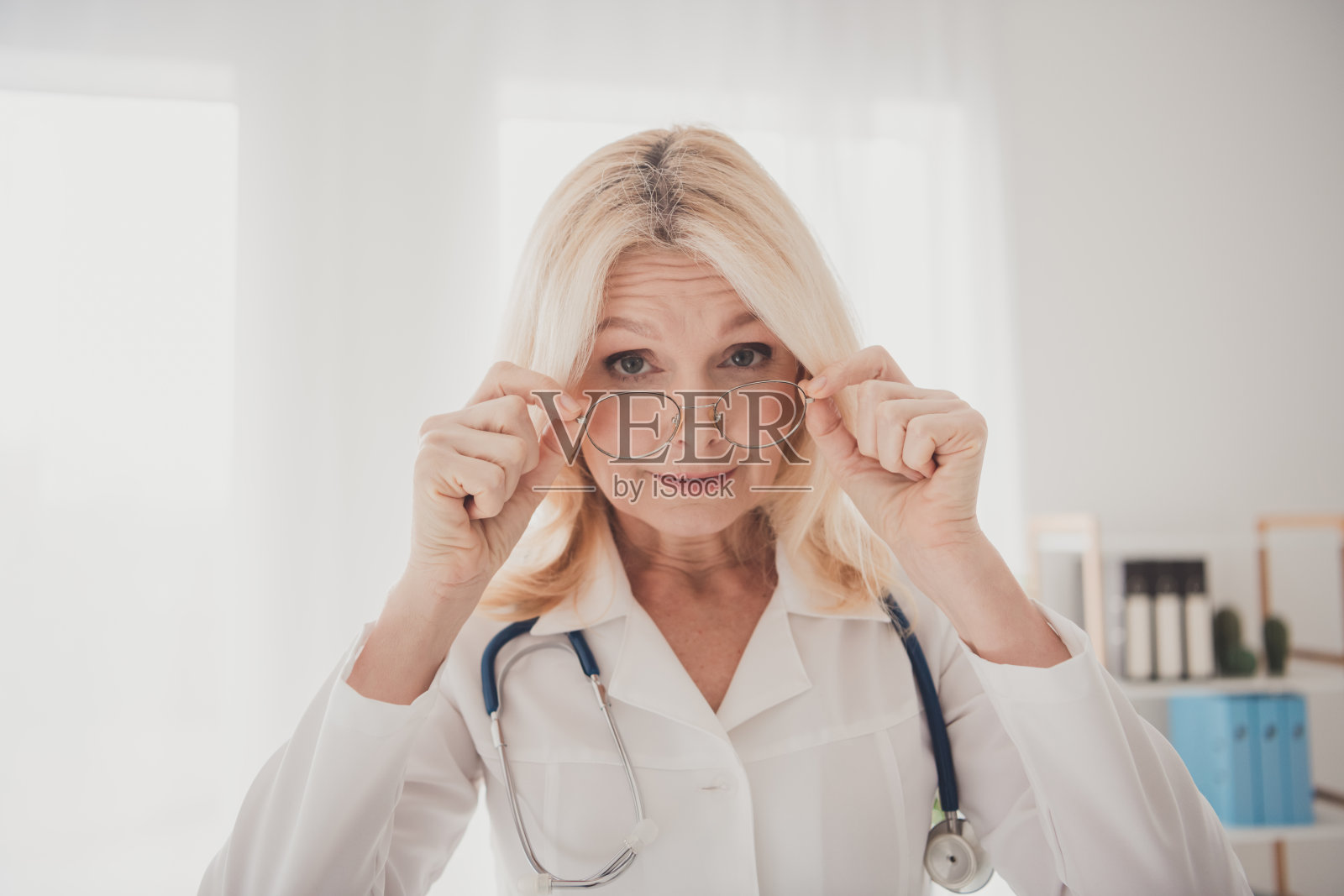 成熟的女医生戴着眼镜，在现代医院办公室专注于患者的护理和咨询。照片摄影图片