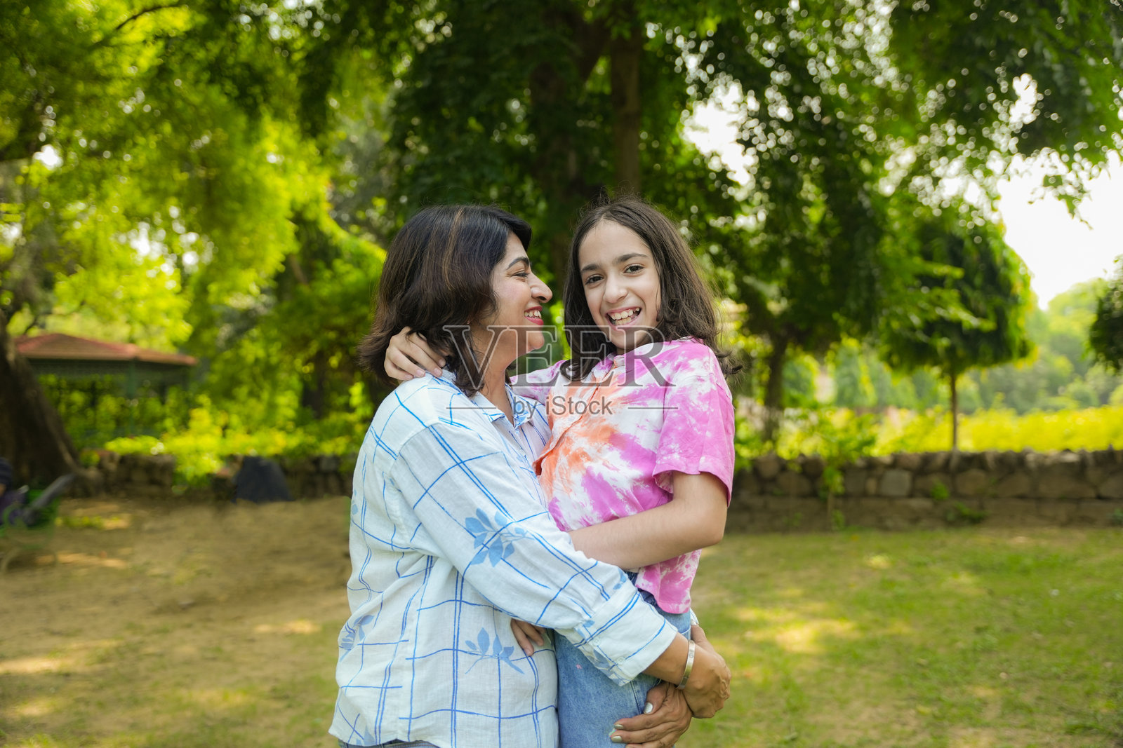 年轻的印度母亲肩上扛着女儿，享受共度时光。亲密的互动，玩耍，假期，度假概念。照片摄影图片