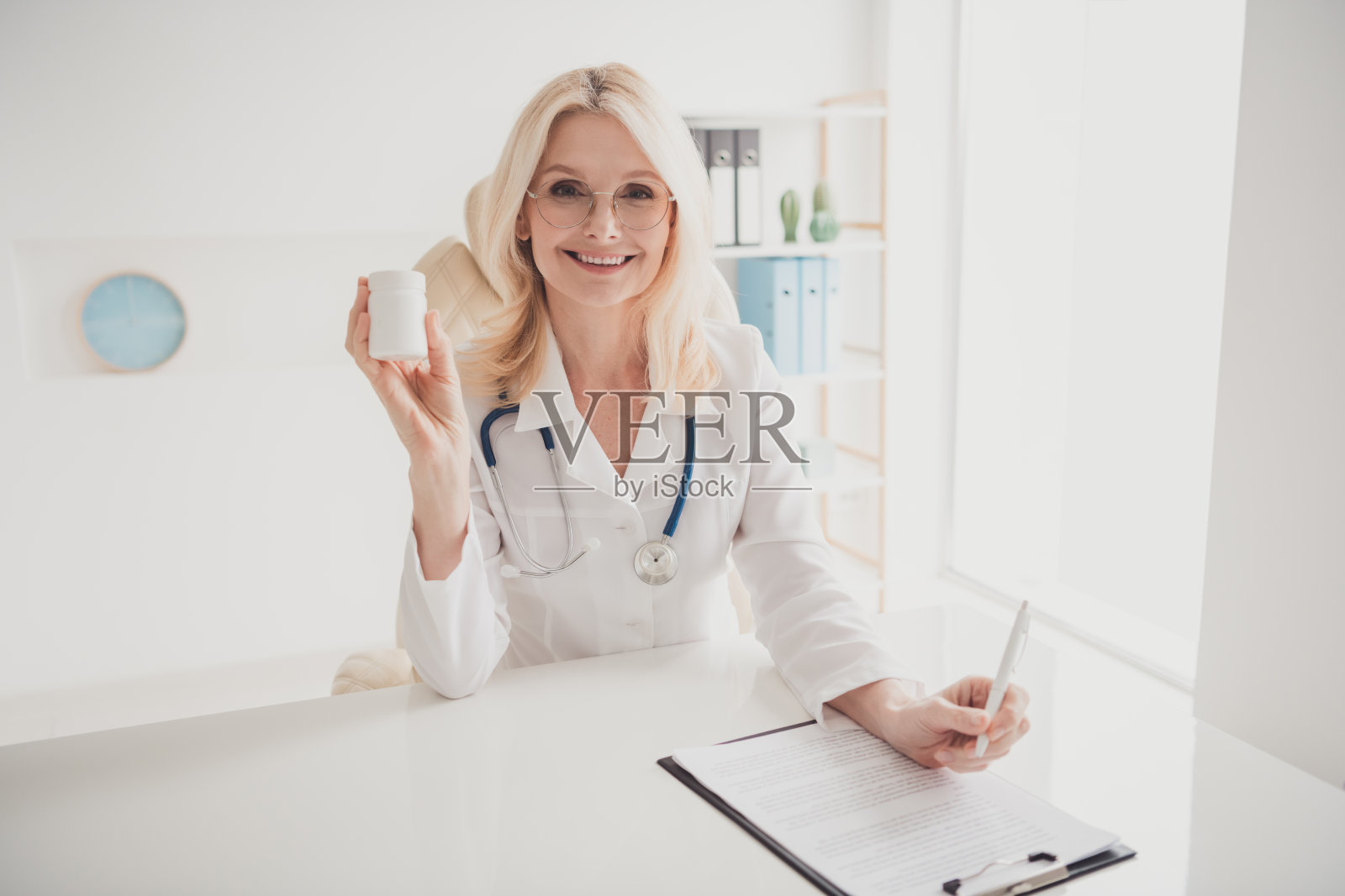 经验丰富的女性医生在诊所办公室手持药瓶提供医疗咨询照片摄影图片