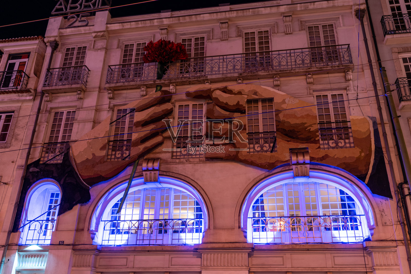 建筑外立面的街头艺术，展示了一只手递给另一只手一朵康乃馨，象征着葡萄牙革命。照片摄影图片