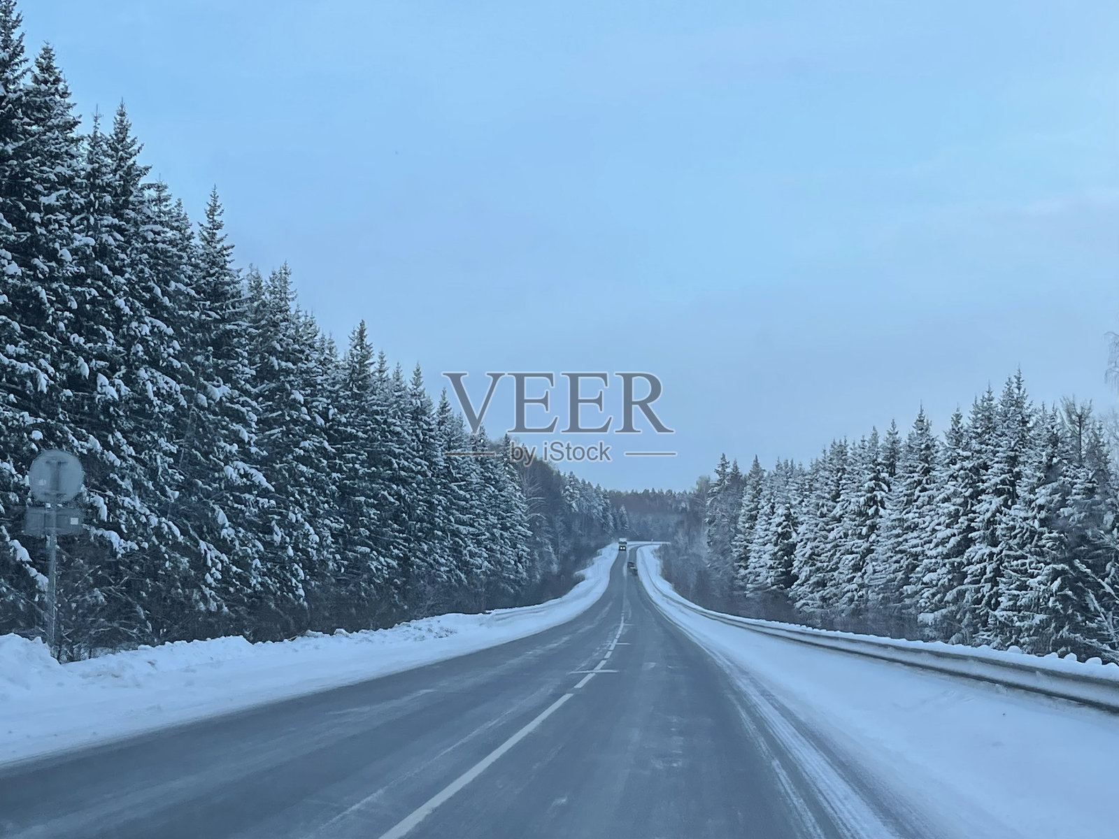 这条路穿过一片被雪覆盖的冬季森林照片摄影图片