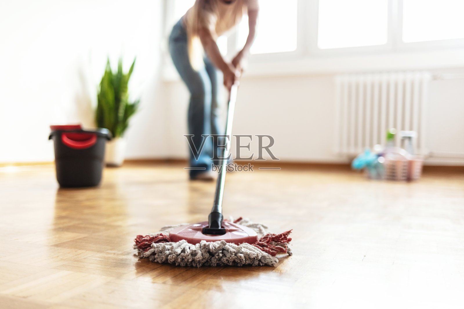 年轻快乐的女性在新公寓里拖卧室地板，清洁她的家。底部视角的快乐女性正在用拖把清洁复合地板。照片摄影图片
