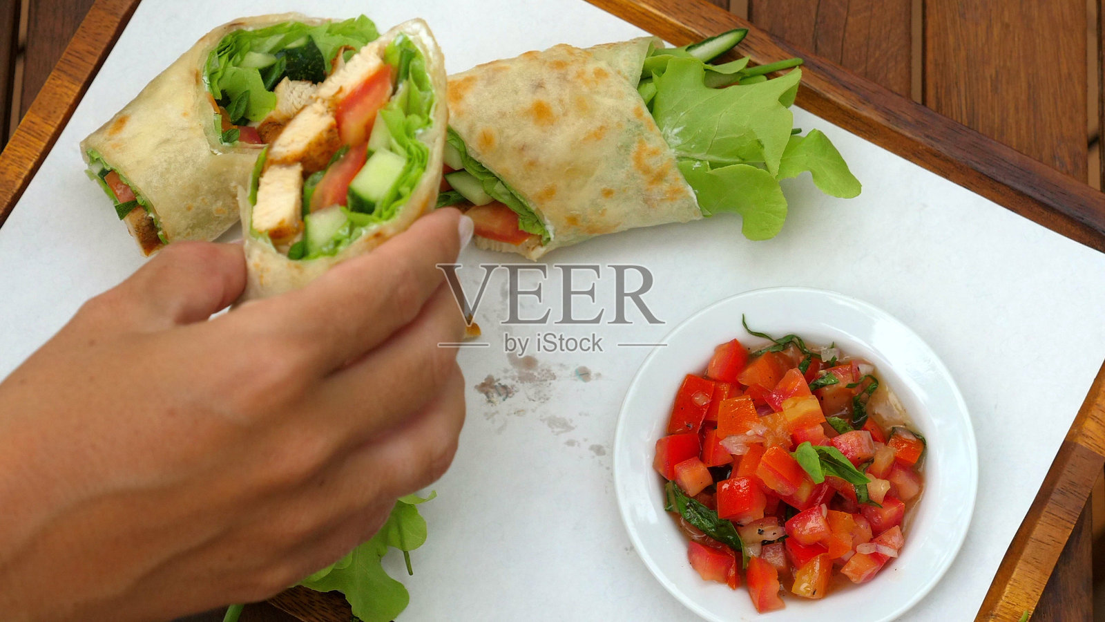 手握新鲜的蔬菜卷，里面有芝麻菜、西红柿和烤制的食材照片摄影图片