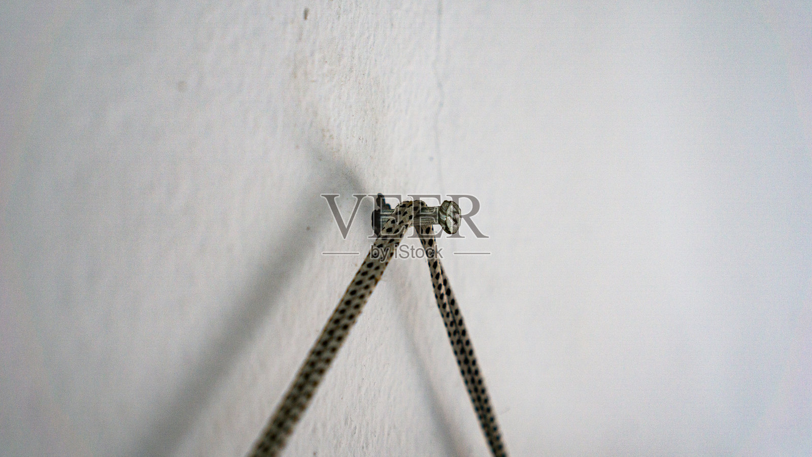 绳子挂在钉子上，钉在白色墙壁上照片摄影图片