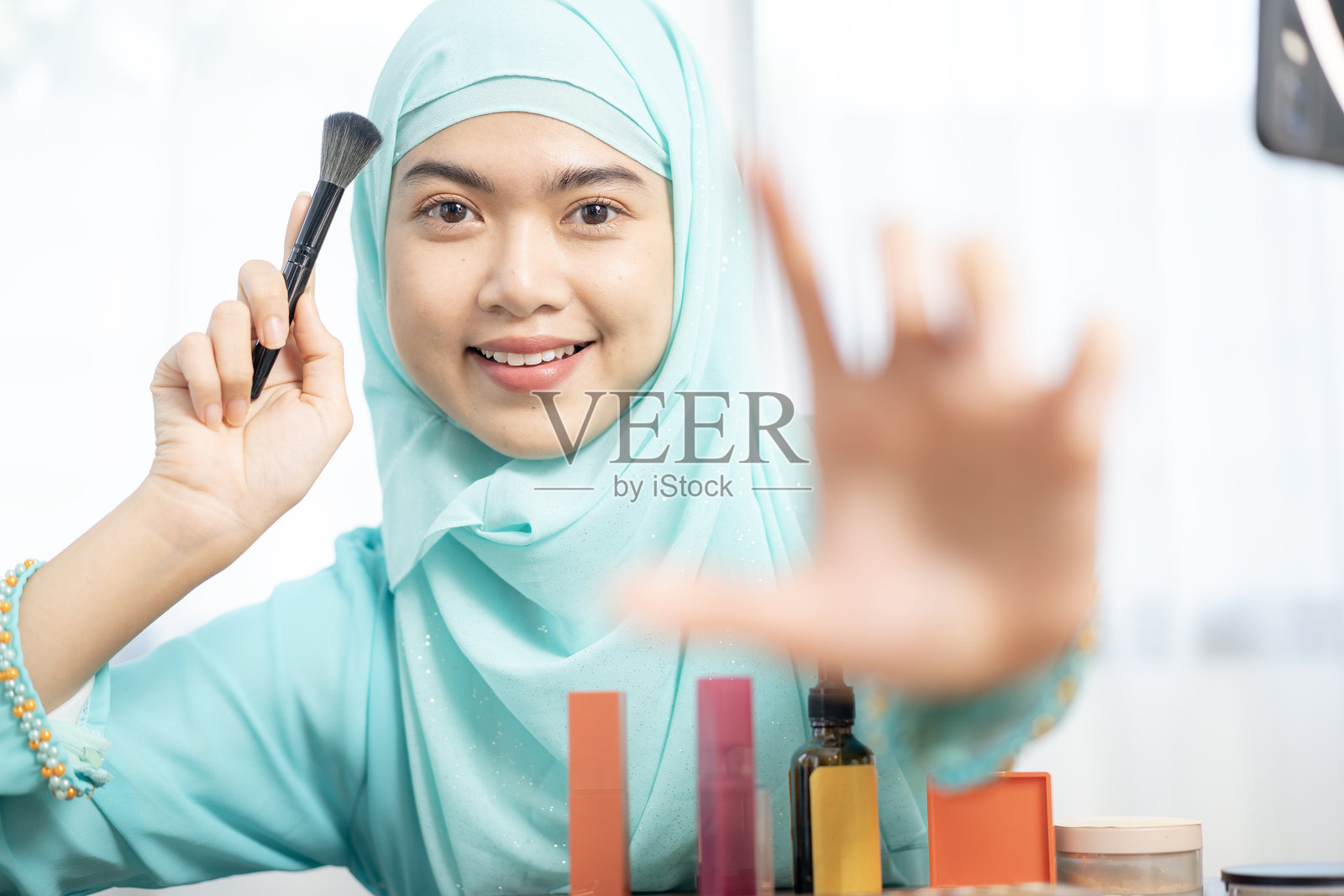 一位年轻女性美容博主正在使用环形灯通过智能手机录制视频博客。照片摄影图片