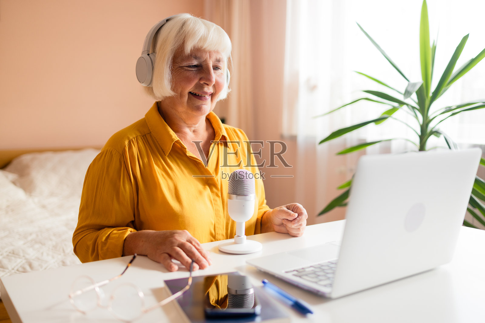 女性播客主持人使用智能手机，通过麦克风与观众交流并录制视频播客。照片摄影图片