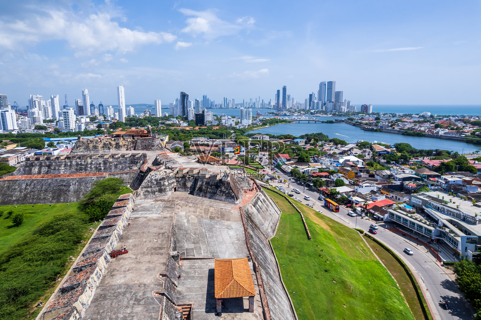 美丽的航拍视角，展示了圣费利佩城堡，巨大的卡塔赫纳国旗在飘扬，背景是城市风景。照片摄影图片