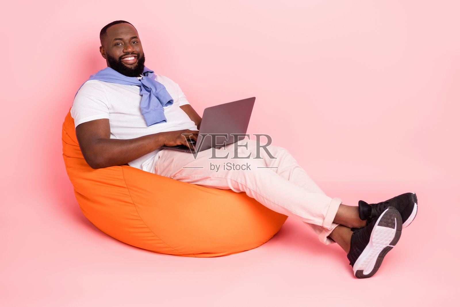 全身照的心情愉快的商人在粉色背景下使用笔记本电脑工作新项目照片摄影图片