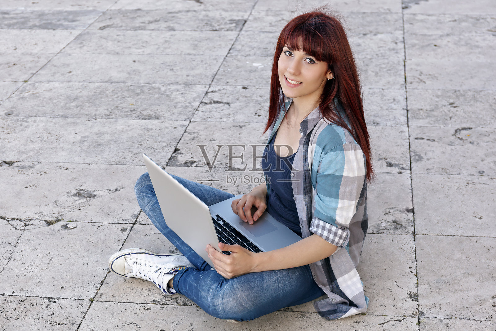 年轻女性坐在人行道上使用笔记本电脑的肖像照片摄影图片
