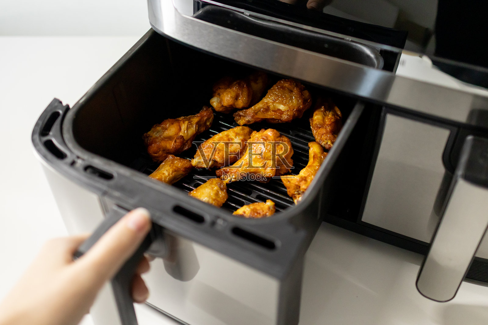 厨房中空气炸锅烹饪的鸡翅特写。照片摄影图片