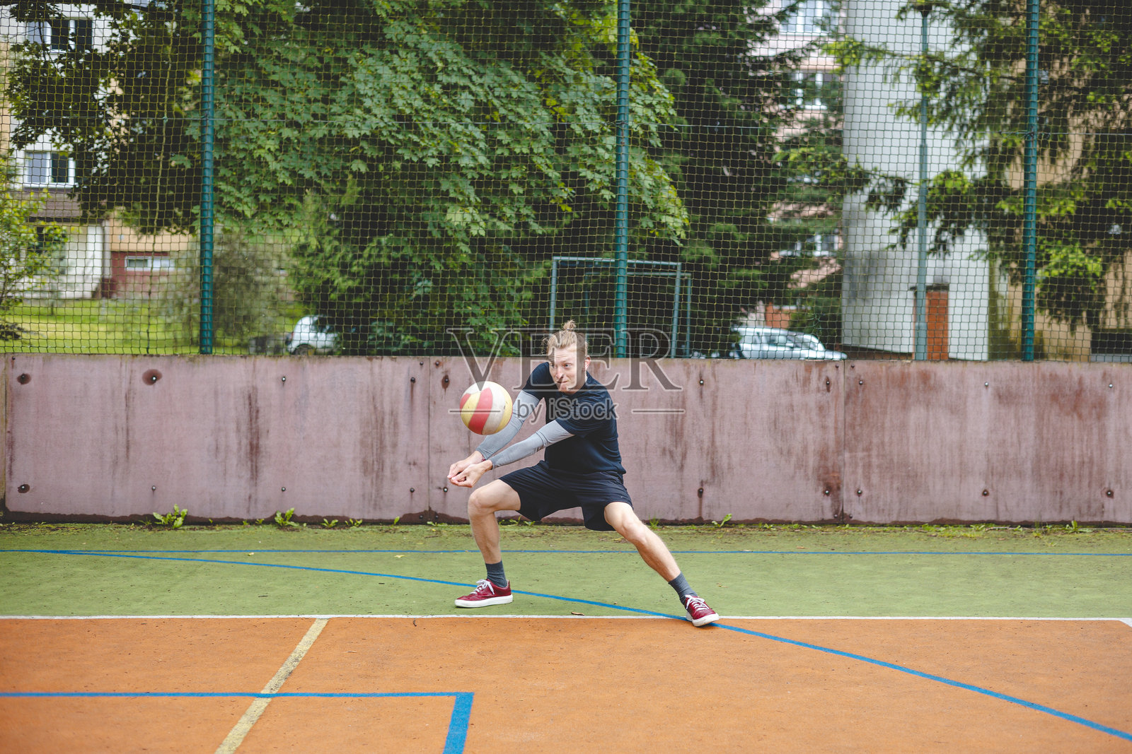 排球运动员在硬地场上进行防守，专注地盯着球，在激烈的比赛中展现出技巧、专注和运动能力。照片摄影图片