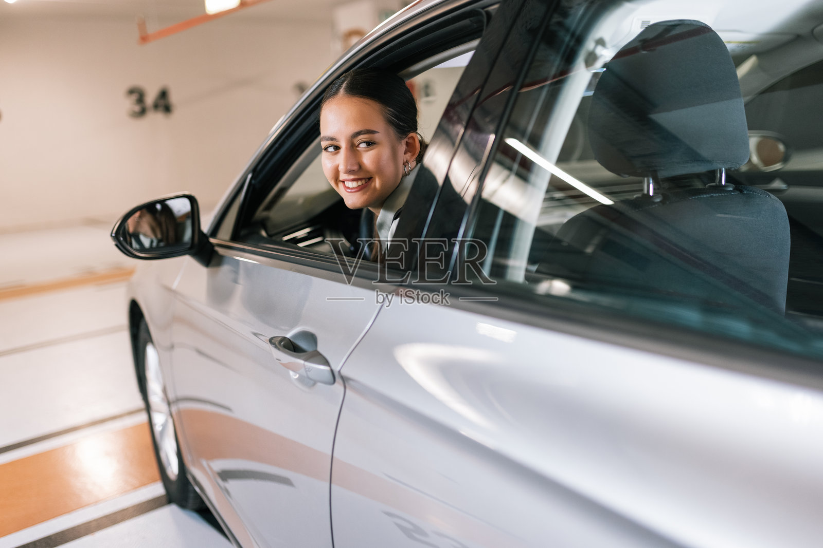 女商人在地下车库倒车停车。照片摄影图片