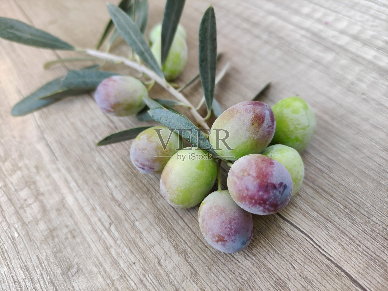 新鲜自然的绿色橄榄连同叶子在木质背景上展示照片摄影图片