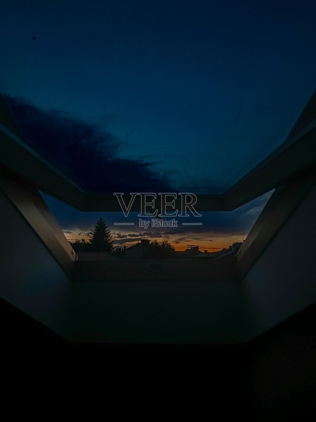 现代房屋屋顶的黄昏日落，透过敞开的窗户。照片摄影图片