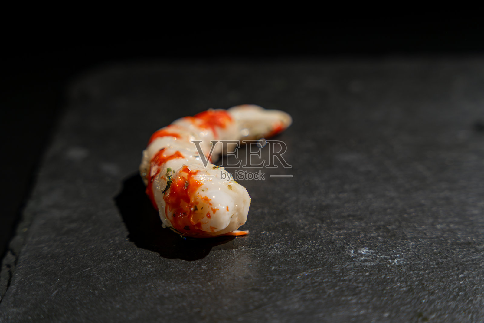 虾形状的仿虾肉放在黑色表面上照片摄影图片