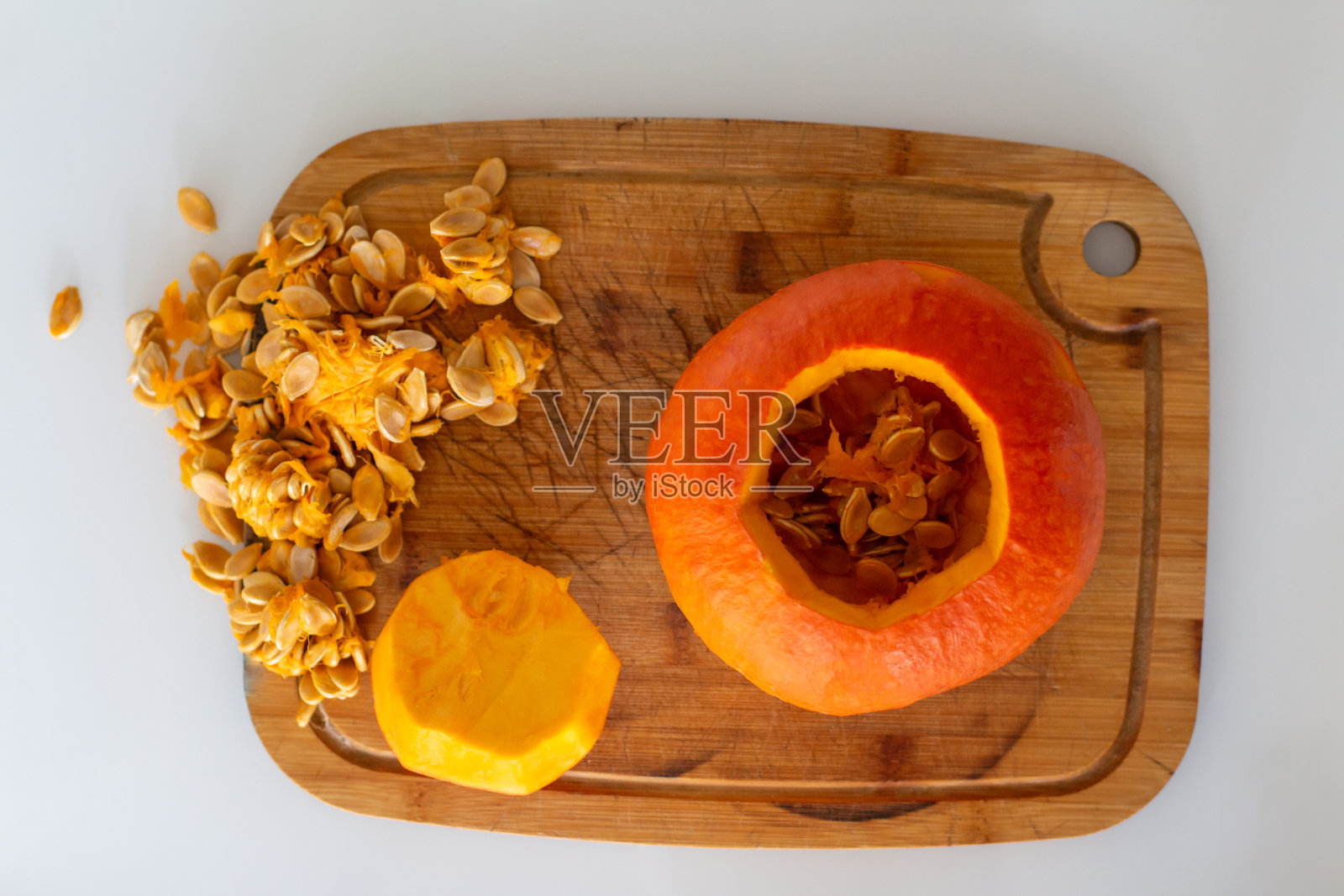 在雕刻南瓜灯之前，清理万圣节南瓜的内部。用刀从切下的顶部盖子中取出南瓜里的果肉和种子。照片摄影图片