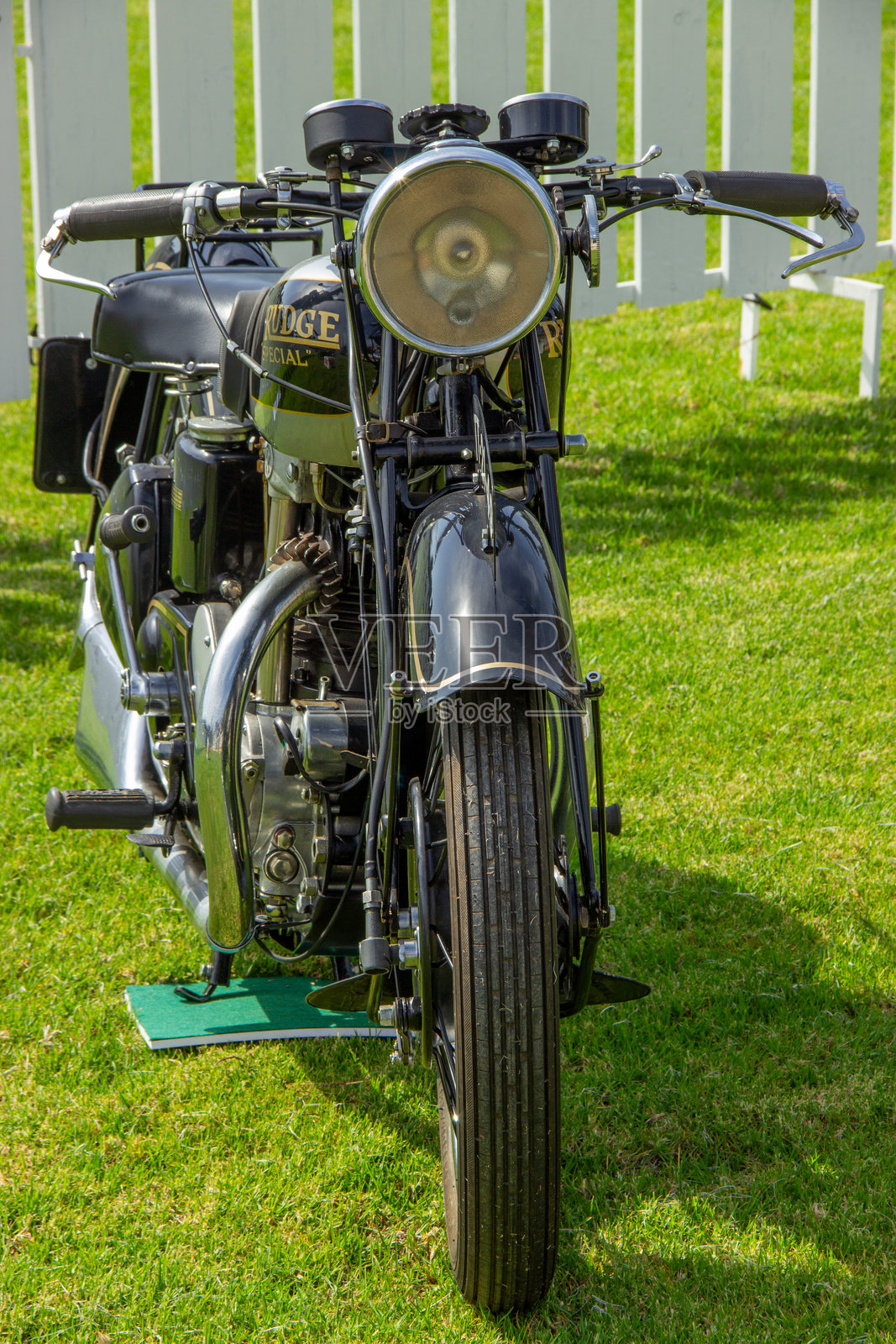 复古的Rudge特制摩托车停在白色围栏前的草地上照片摄影图片