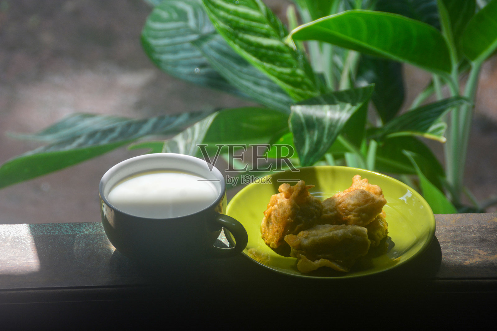 炸香蕉和热咖啡的特写。早晨在家阳台上享用炸香蕉和热咖啡，这是印尼人养成的习惯，有些人甚至将其视为早餐。照片摄影图片