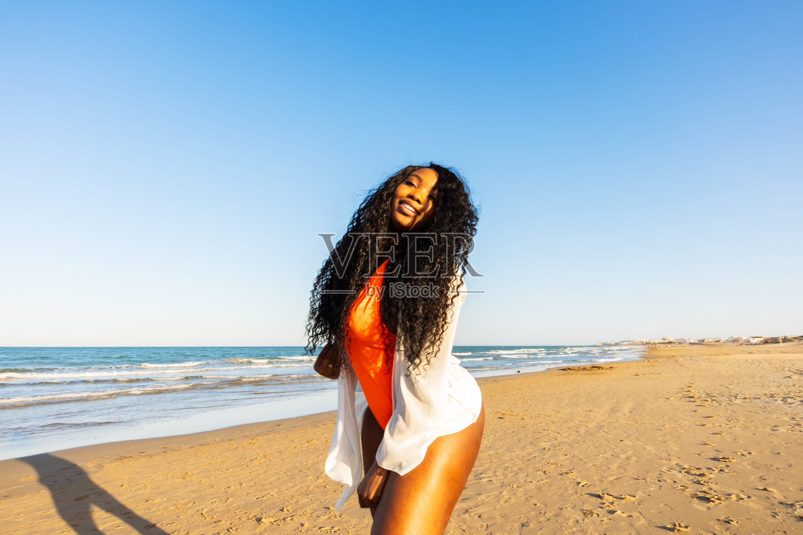 微笑的非洲裔美国黑肤女性在海面上行走。夏季周末，跨种族女性在天空地平线上。混血人群，种族，多样性。照片摄影图片