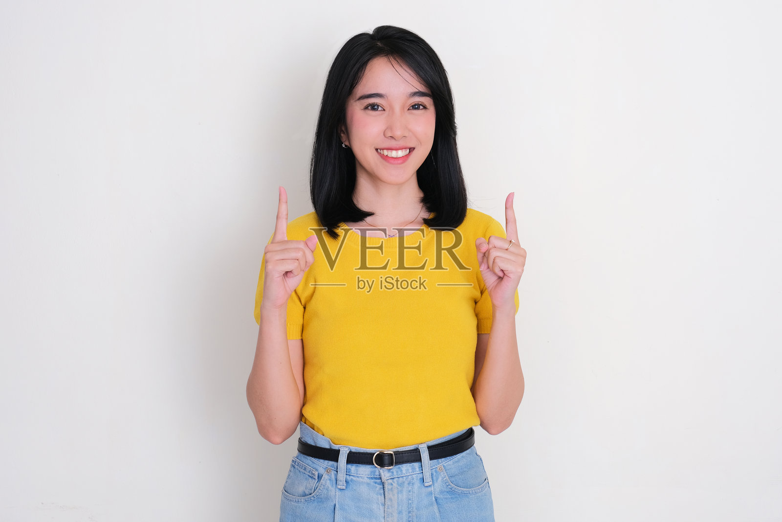 亚洲女性微笑着看向镜头，双手指向头顶。照片摄影图片