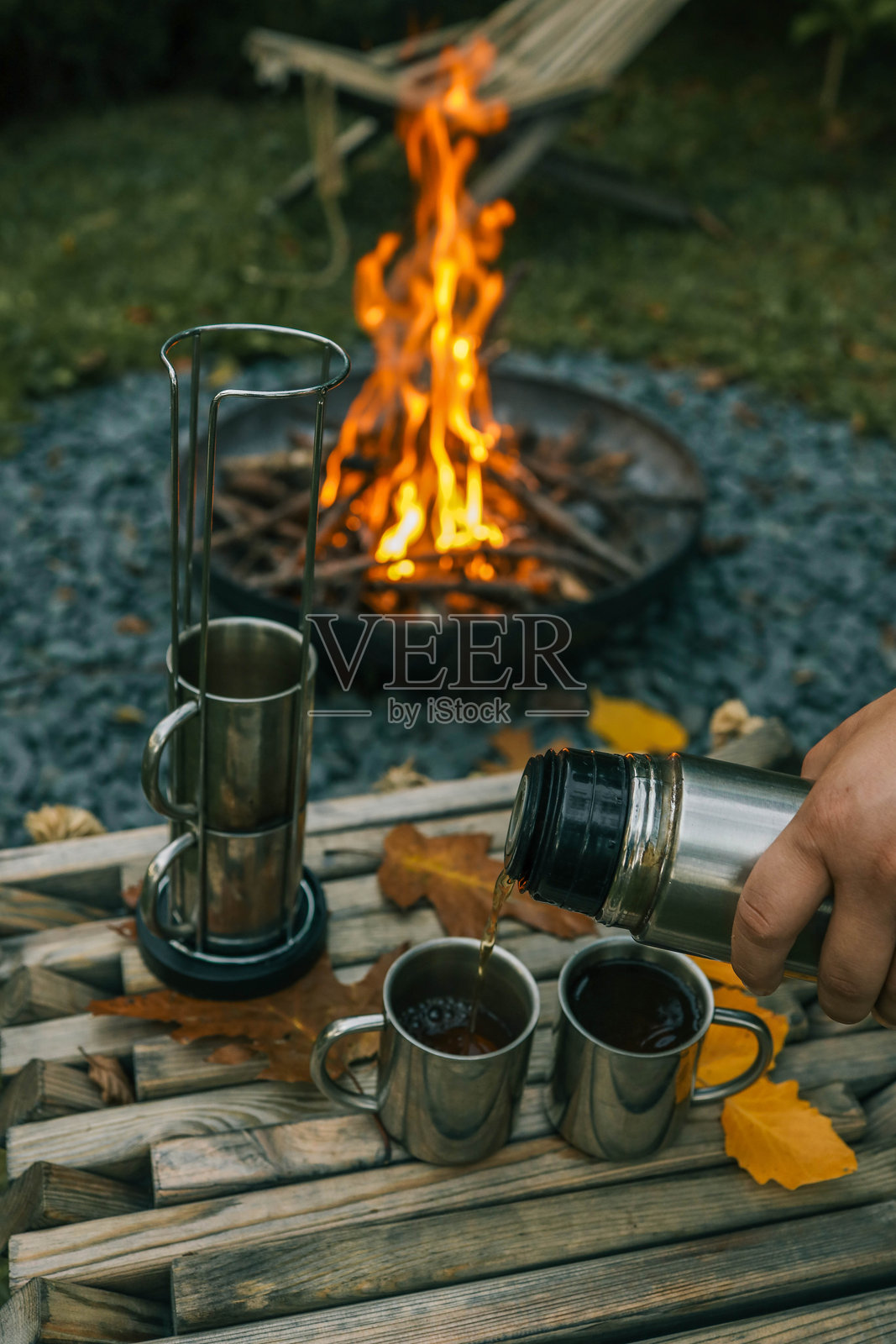 主题旅行。男人将热饮倒入保温瓶中。照片摄影图片