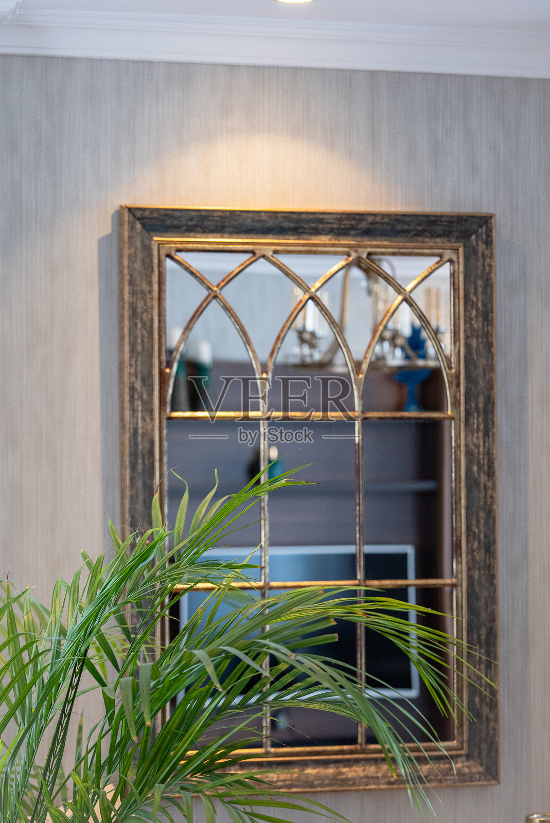 在一座优雅的房子的角落里，一面装饰精美的镜子挂在墙上。照片摄影图片