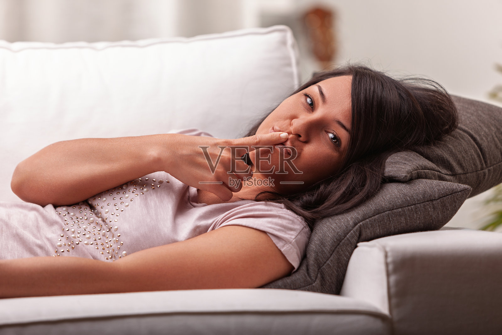 年轻女性坐在沙发上用手指做出安静的手势照片摄影图片