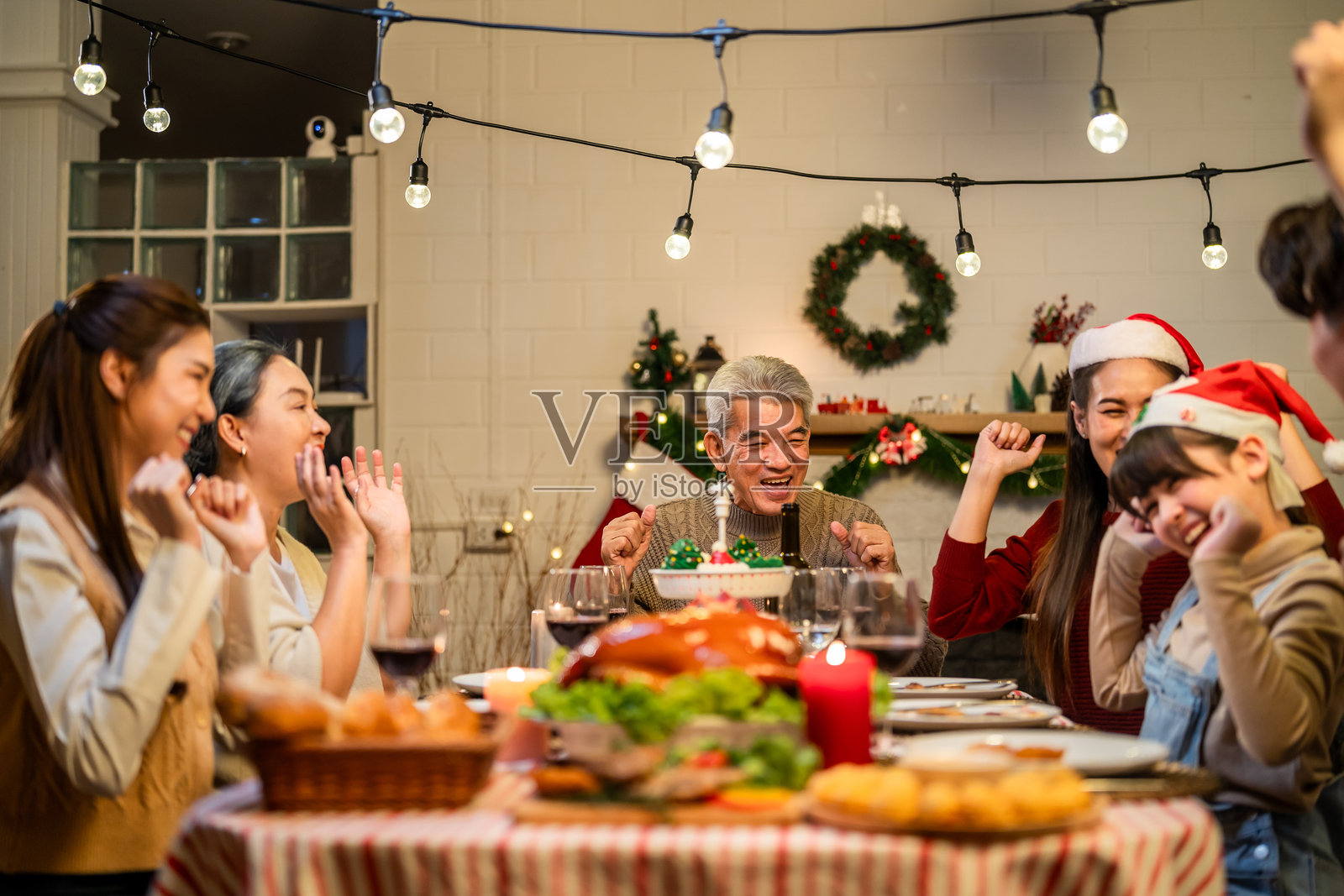 亚洲可爱的家庭在家中庆祝圣诞派对。迷人的父母和亲戚们在餐桌上享用美食，共同庆祝感恩节和圣诞前夕。照片摄影图片