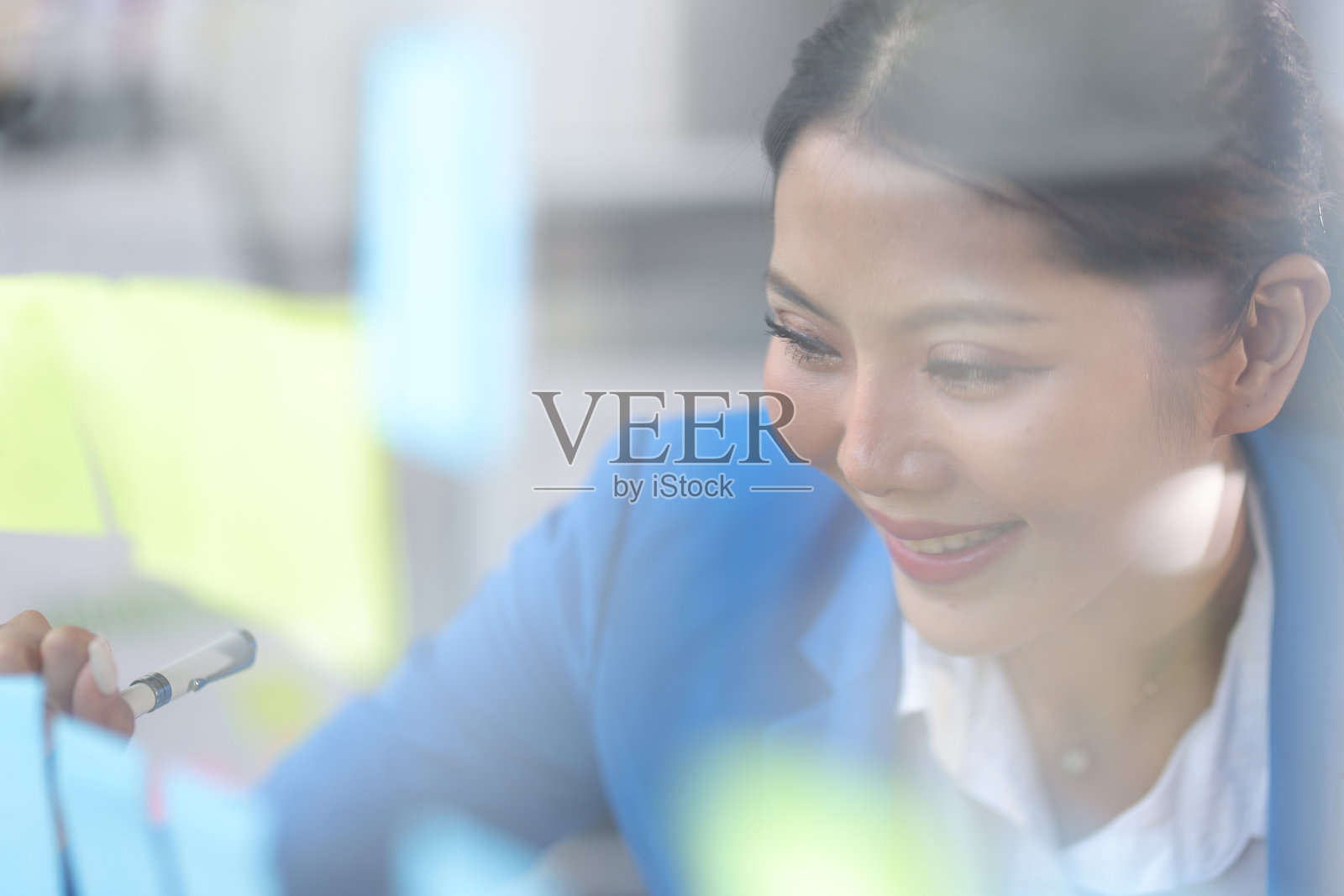 深思熟虑的女商人富有创意地在透明板上用纸贴进行初步商业规划和草图。战略分析与商业规划。照片摄影图片