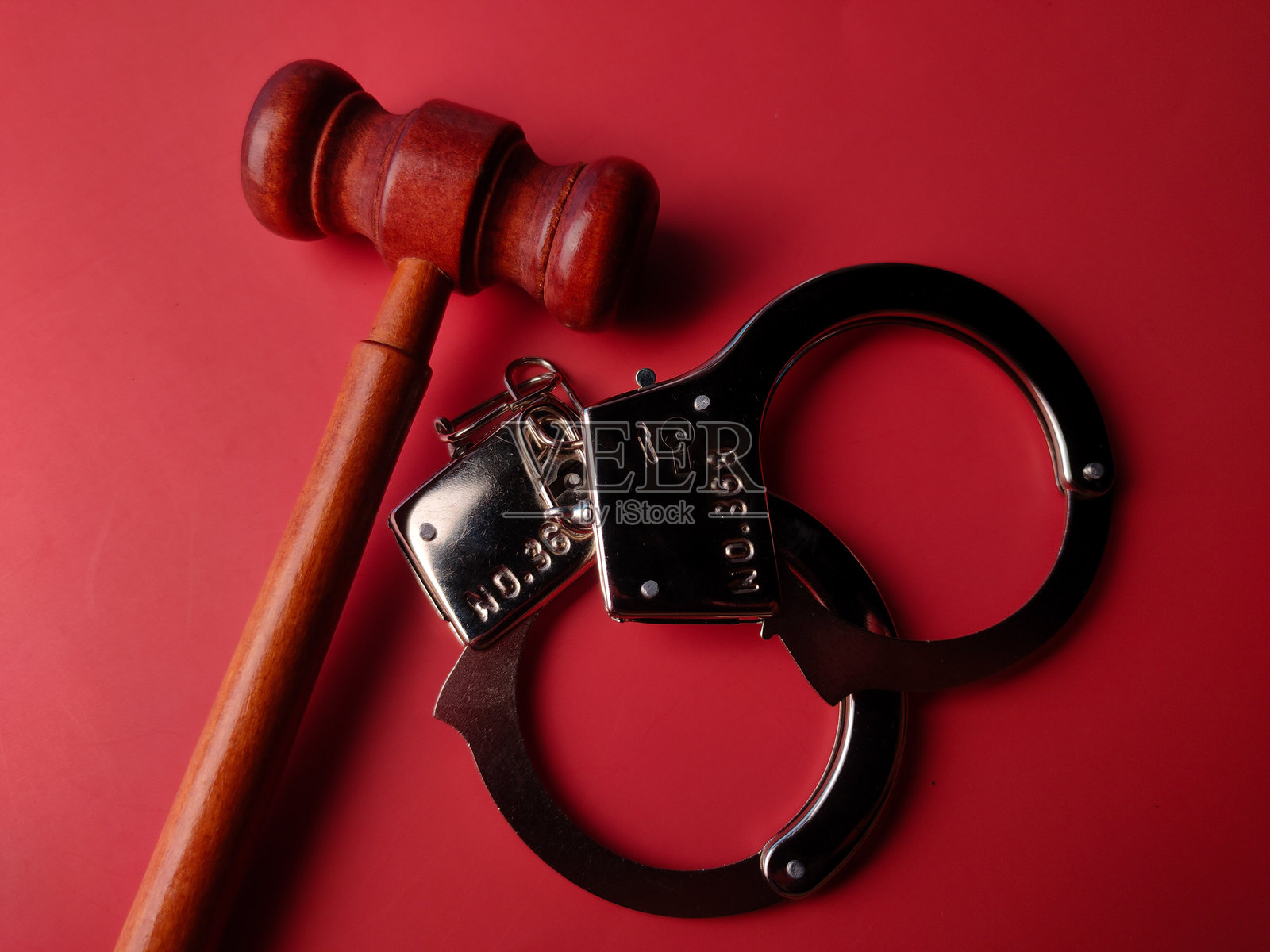 红色背景上的法槌特写和金属手铐照片摄影图片
