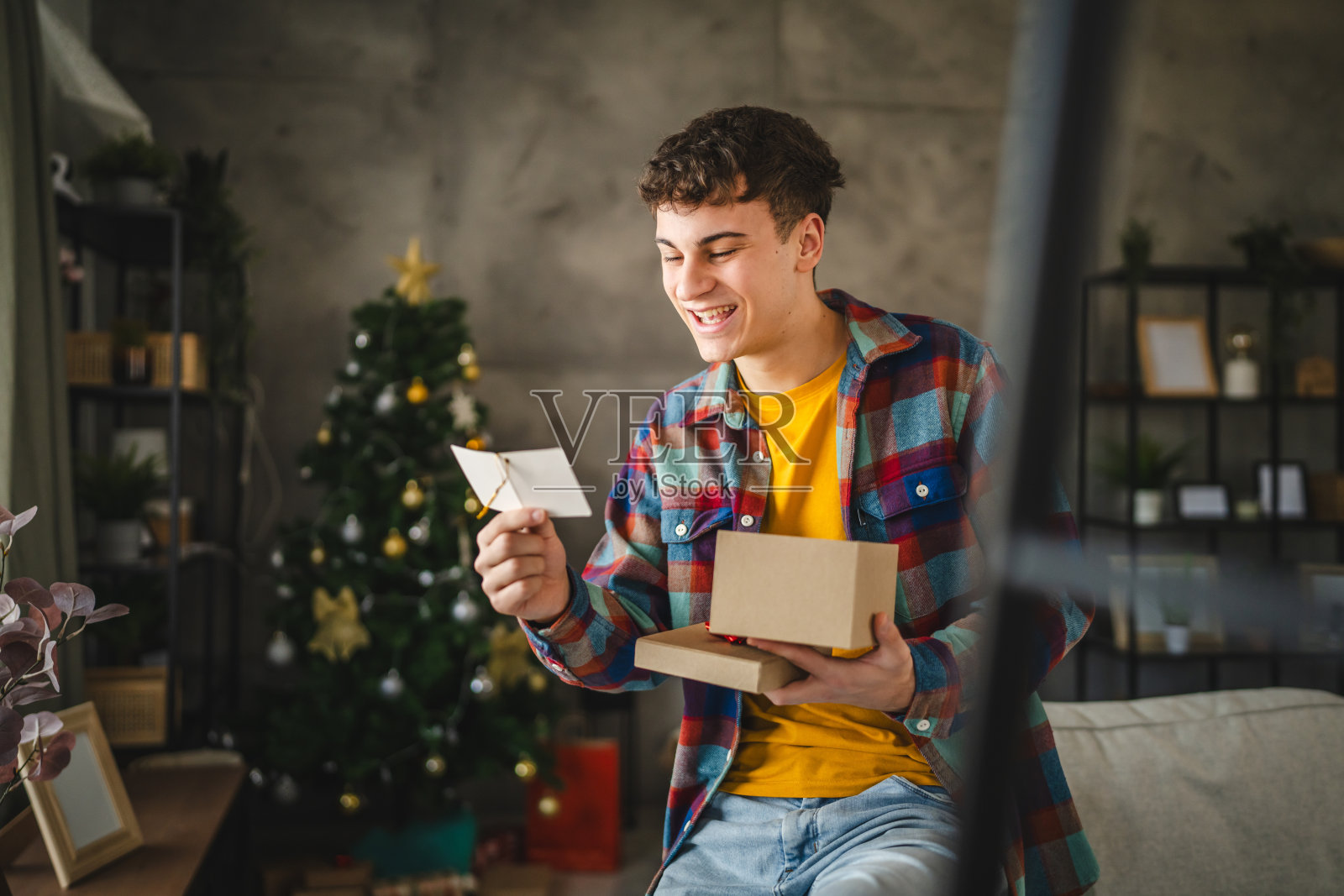 年轻男子从圣诞礼物盒中阅读贺卡照片摄影图片