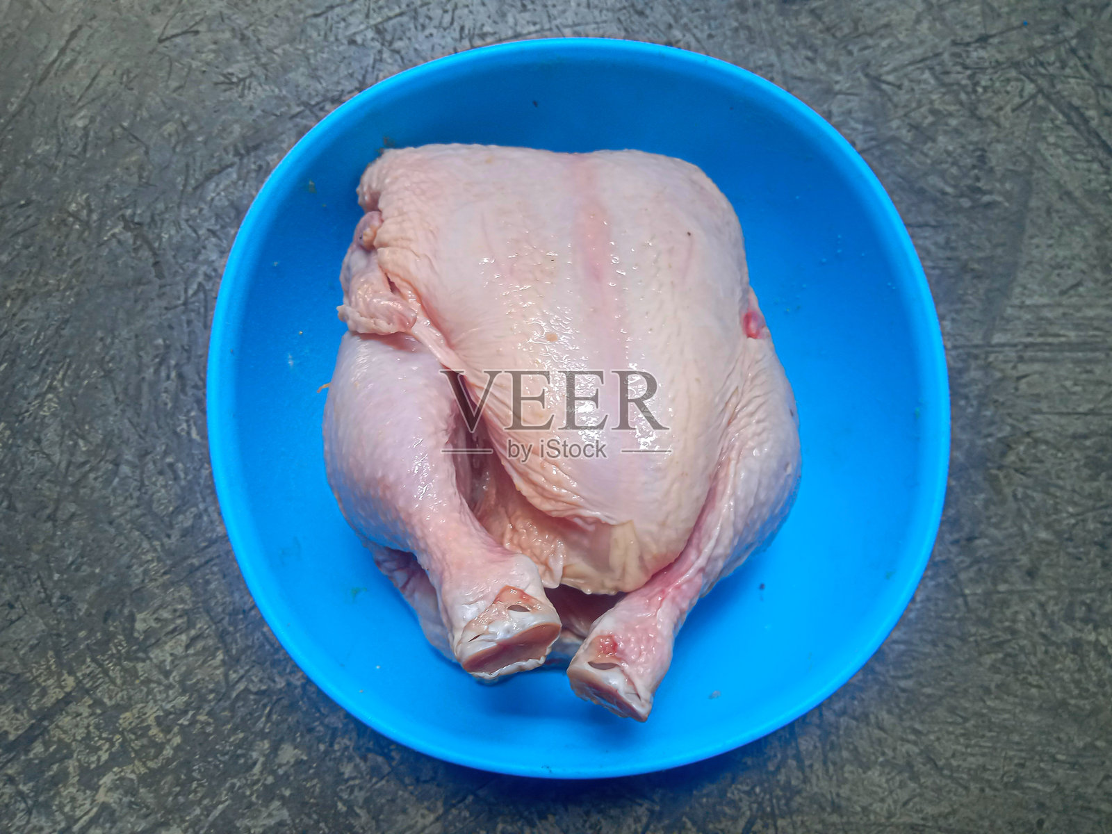 蓝碗中的切块鸡肉，背景为铸铁桌面照片摄影图片