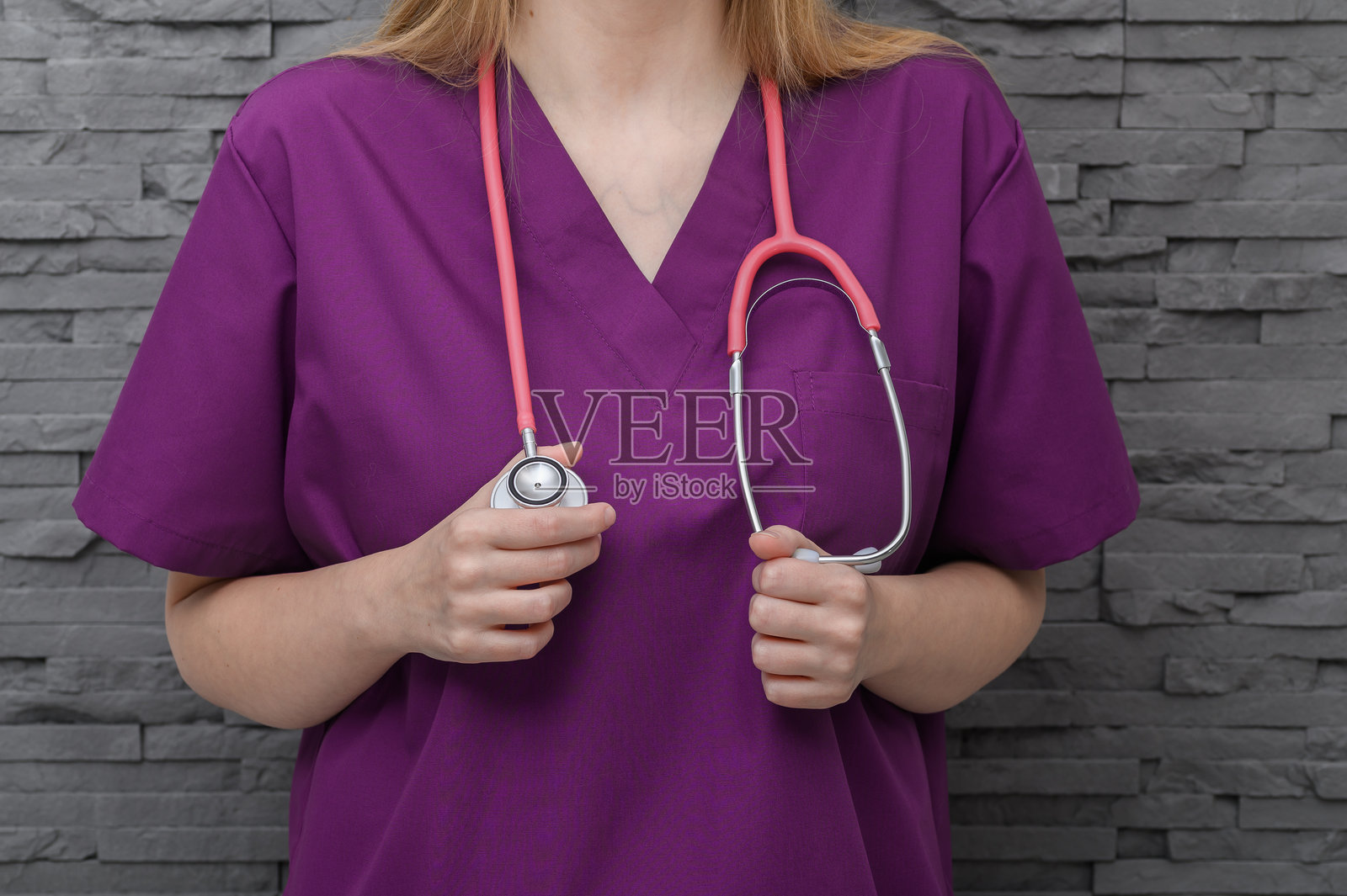 一位年轻女性医生穿着白大褂，脖子上挂着听诊器。照片摄影图片