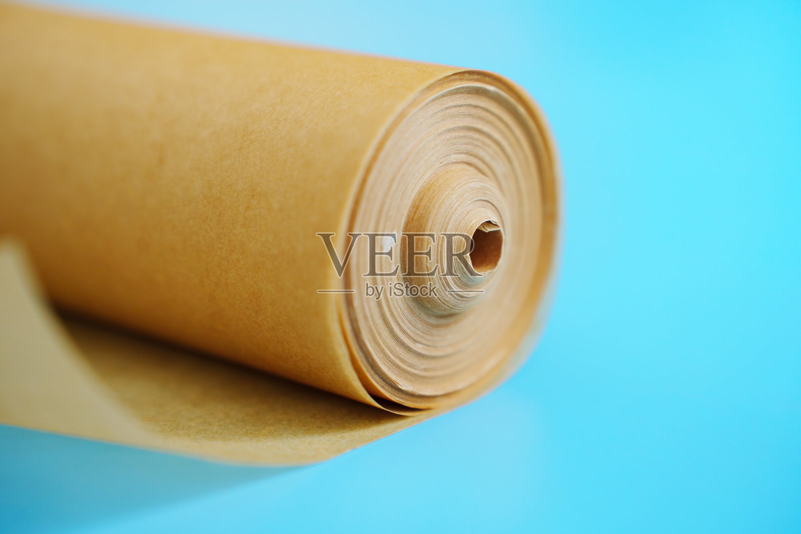 蓝色背景上的一卷烘焙纸。照片摄影图片