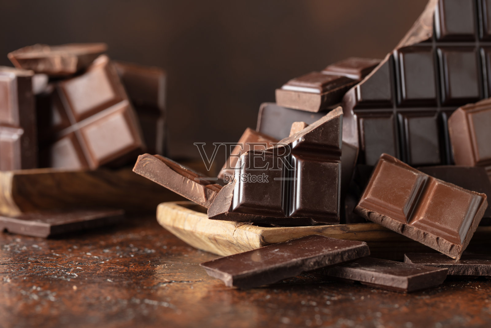 破碎的苦巧克力和牛奶巧克力棒放在棕色背景上。照片摄影图片