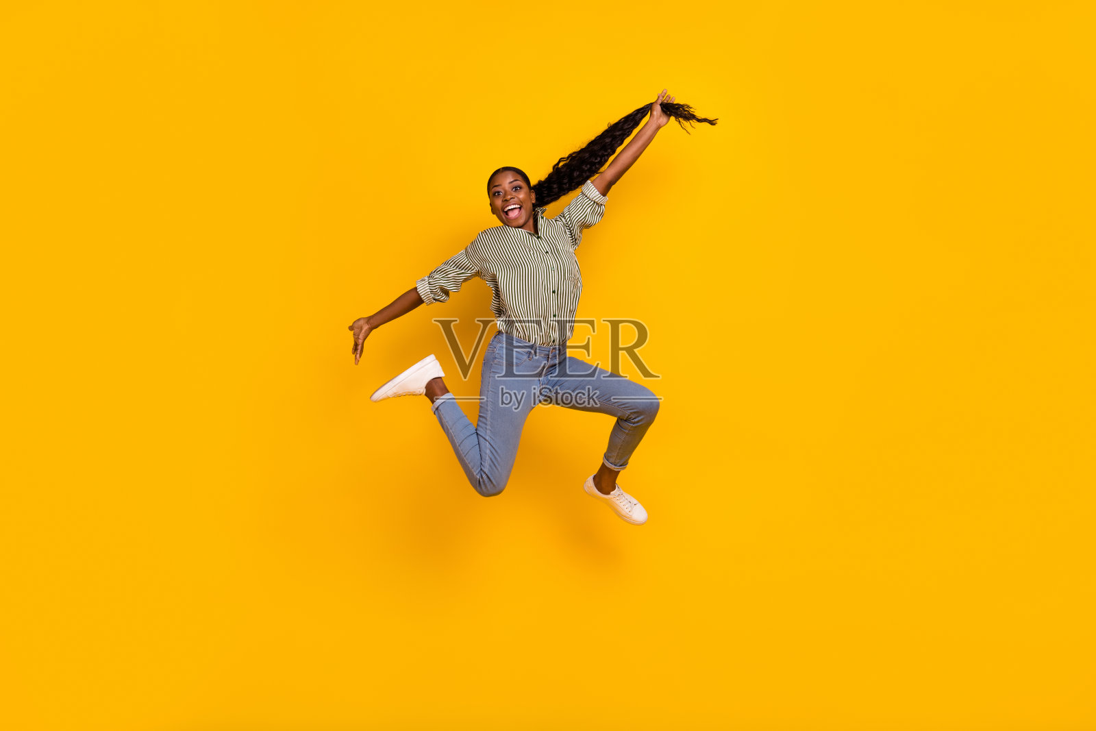 兴奋满意的人全身肖像，手臂托着长发，背景为黄色。照片摄影图片