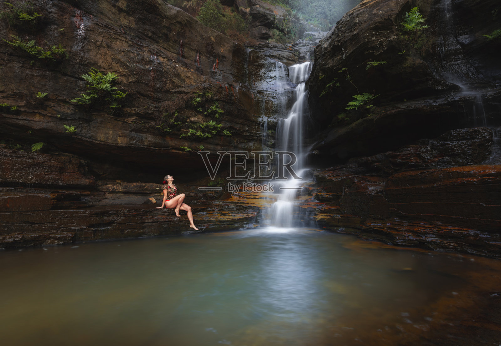 女人在瀑布和游泳池旁享受闲暇时光照片摄影图片