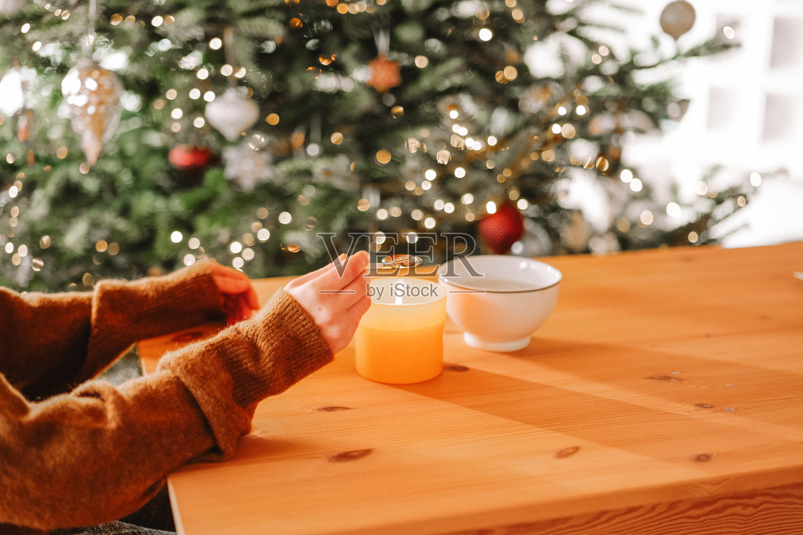 新年派对的锡铸造套件。女人在一个装饰有圣诞树的温馨房间里，蜡烛火焰上熔化锡。女人在手中仔细观察一块熔化的锡。照片摄影图片