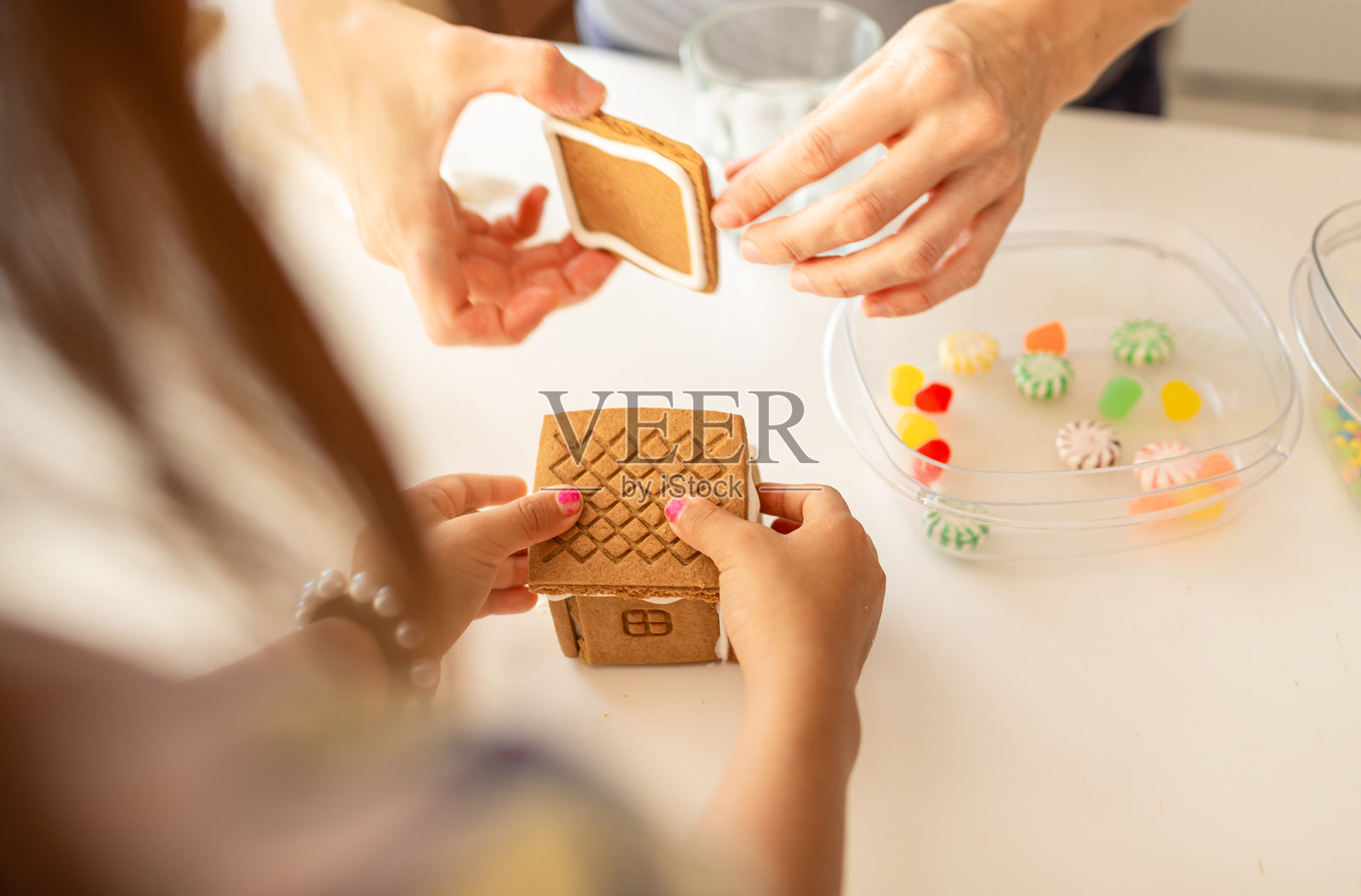 母亲和小孩一起装饰姜饼屋。照片摄影图片