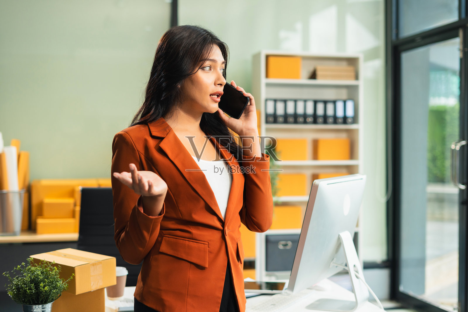 年轻的亚洲女性正在使用智能手机联系客户，询问送货地址。照片摄影图片