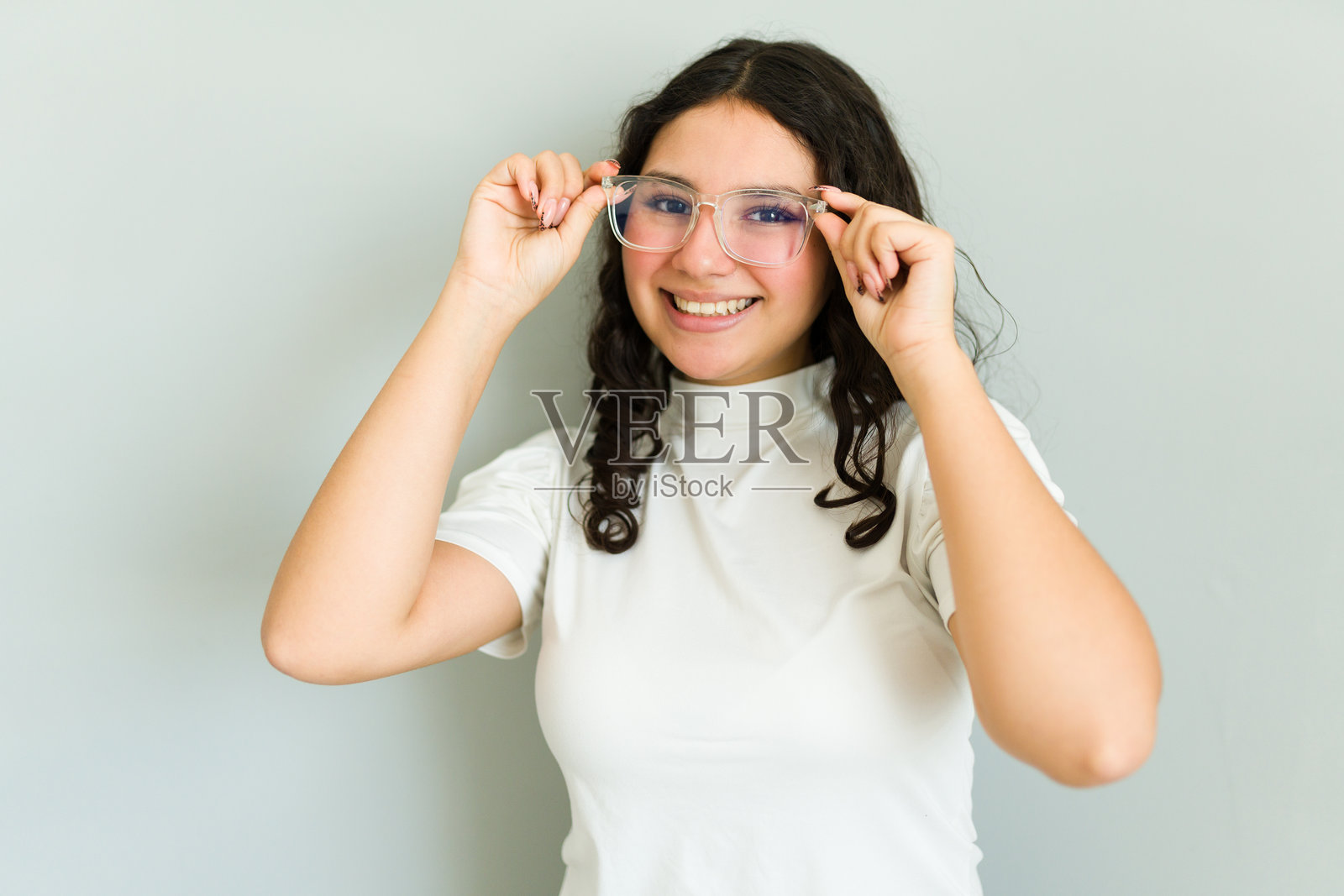 美丽的拉丁裔少女正在调整她的新眼镜，微笑着，享受视力改善带来的快乐。照片摄影图片