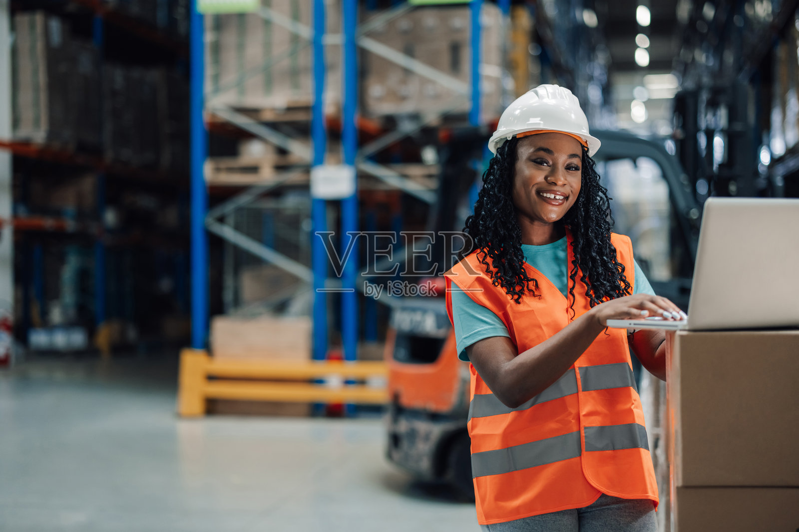 年轻女性员工在仓库里使用笔记本电脑照片摄影图片