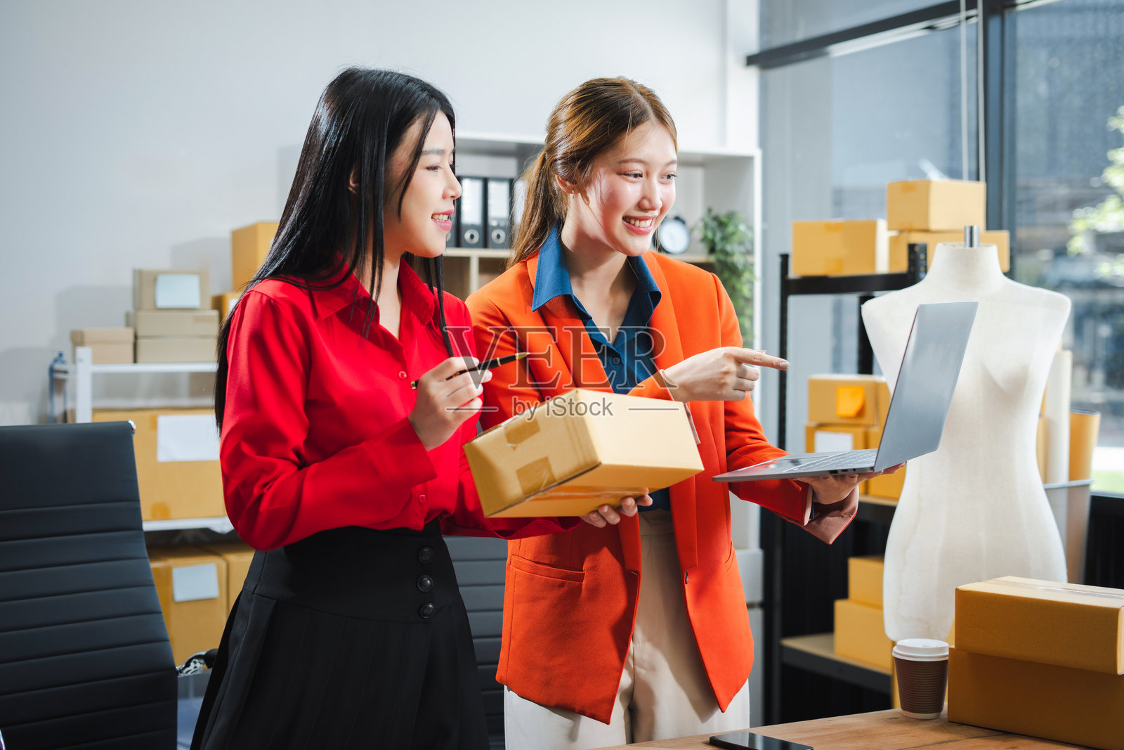 两位年轻的亚洲女性在后台办公室工作，检查仓库中的产品，电子商务概念。照片摄影图片