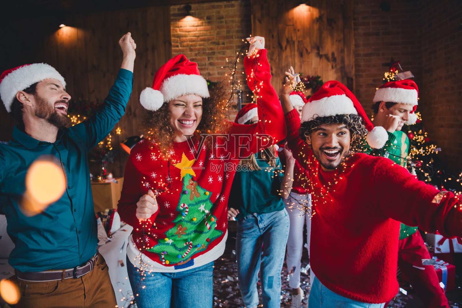 年轻人们在室内派对上享受愉快的舞蹈，周围是温馨的圣诞装饰。照片摄影图片