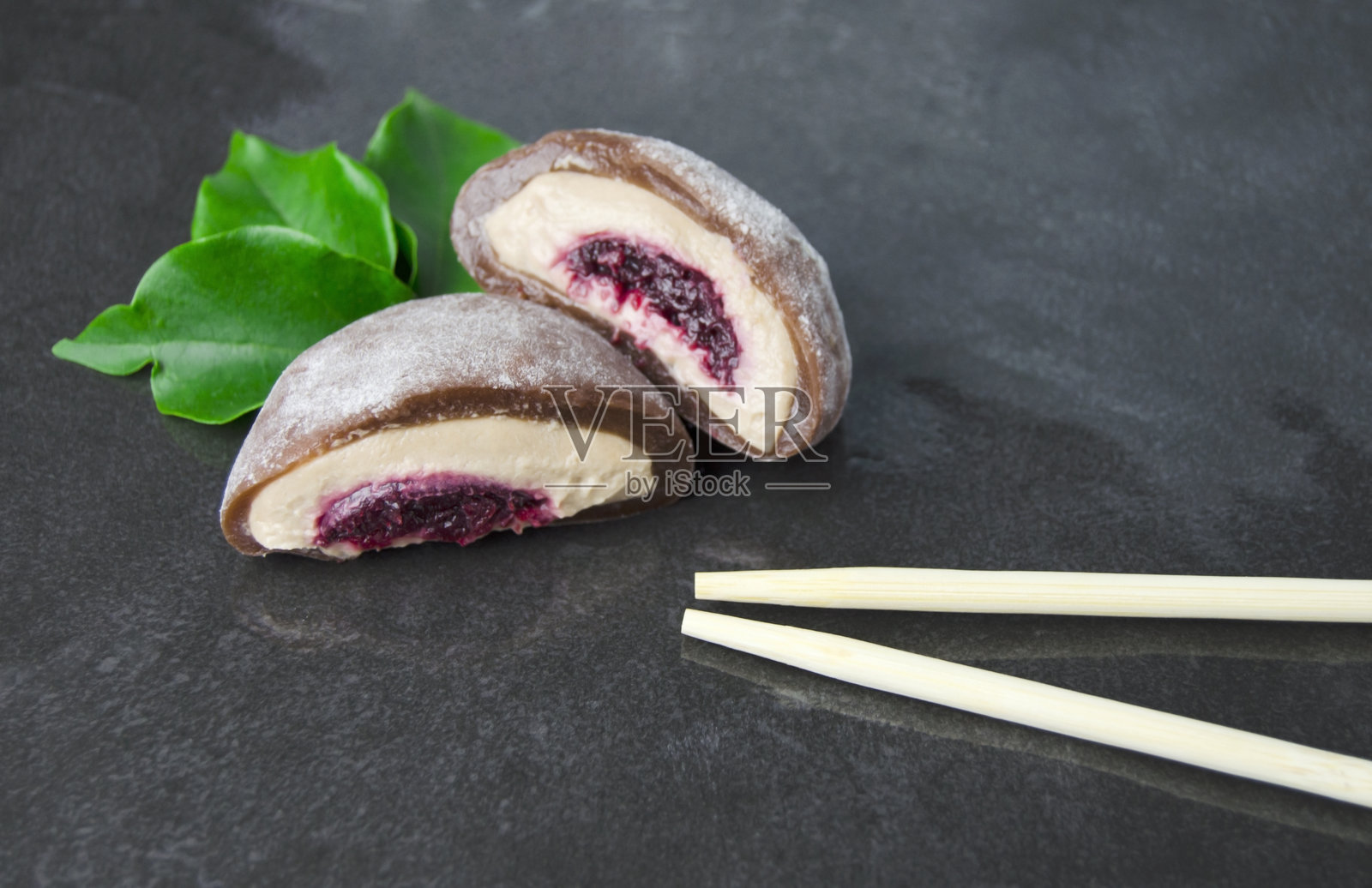 黑色背景上的巧克力麻糬，配有奶酪和樱桃。亚洲美食。日本传统冷冻甜点麻糬。照片摄影图片