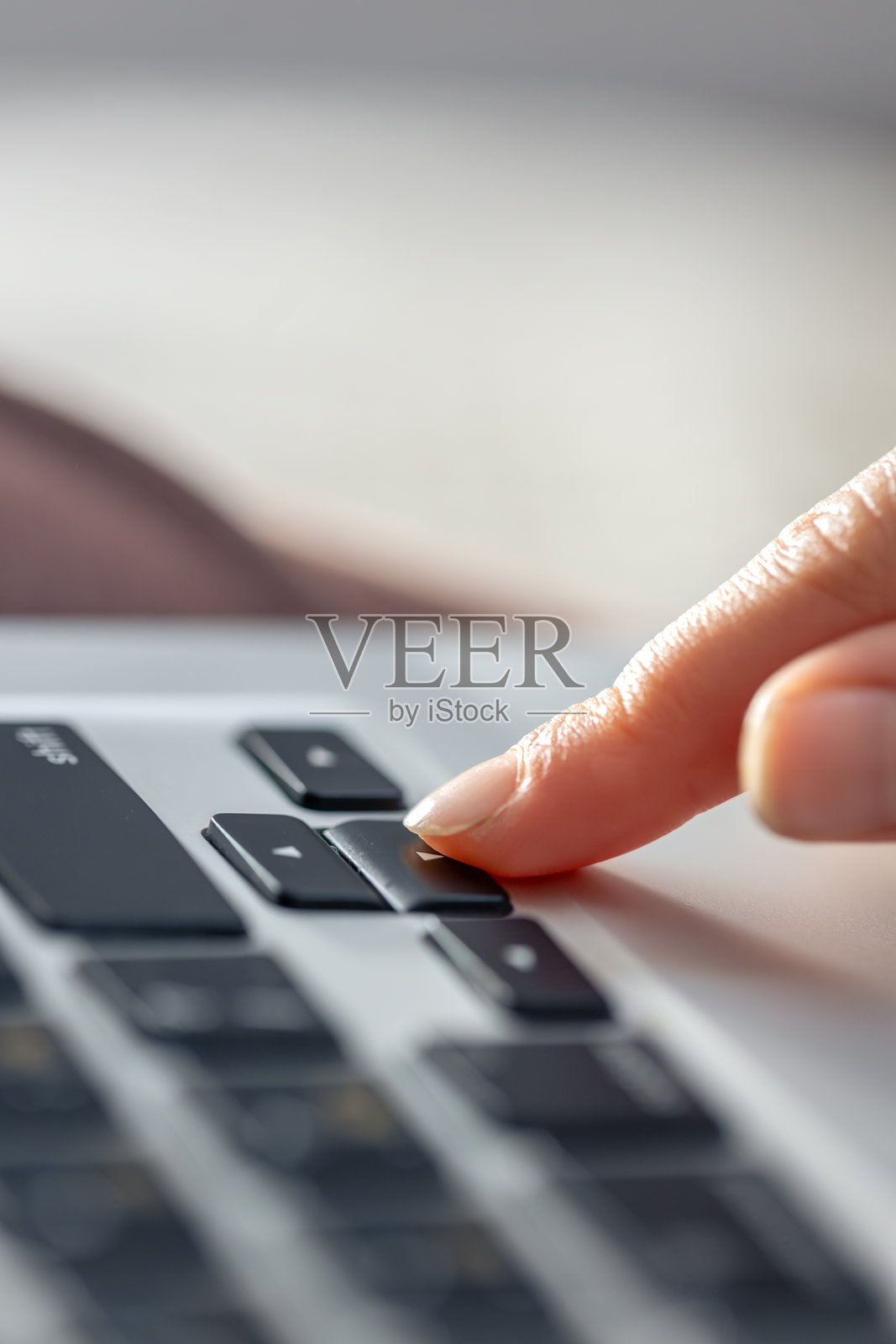 女孩正在笔记本电脑键盘上打字。女孩的手放在键盘上。照片摄影图片