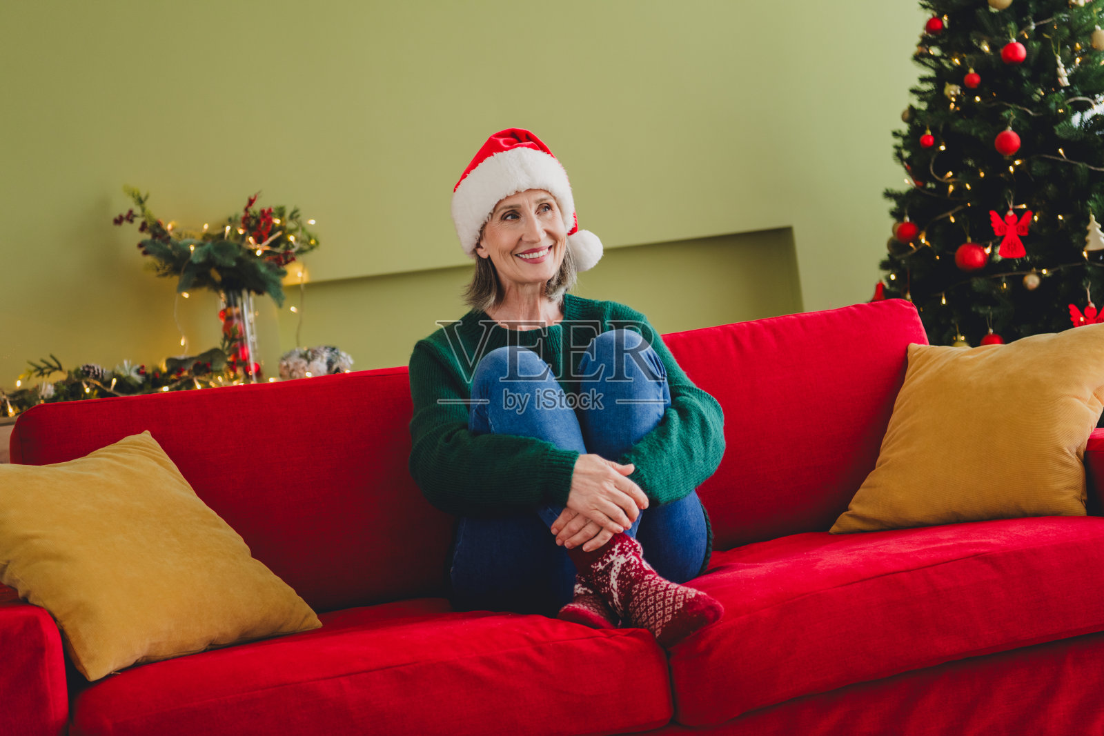 可爱的迷人女士穿着绿色衣服，坐在沙发上享受圣诞假期，舒适地度过新年周末，室内环境温馨。照片摄影图片