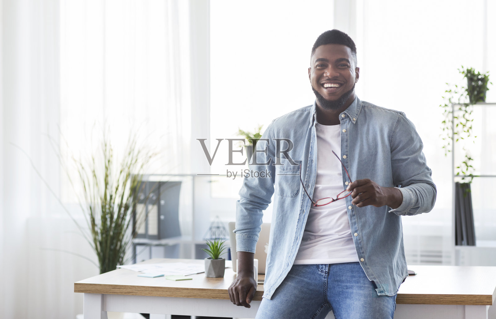 成功的商人靠在办公桌上，注视着镜头照片摄影图片