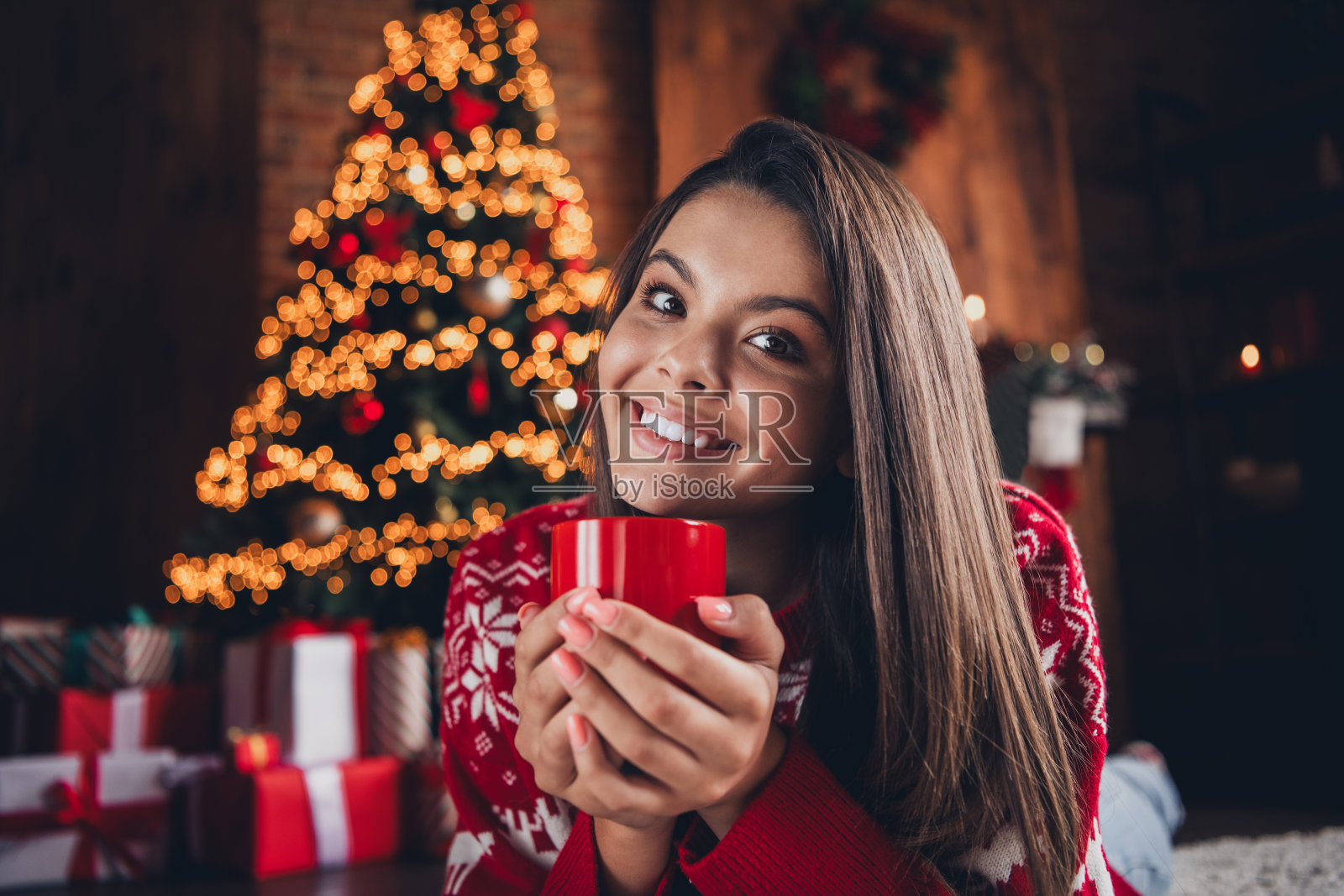可爱的女孩穿着新印花衣服，躺在地毯上，享受圣诞周末的节日气氛，房间内装饰一新。照片摄影图片